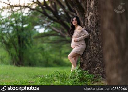 young happy beautiful pregnant woman stroking her belly in the park