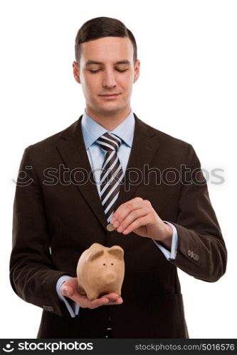 Young happy business man putting money in the piggybank over white background