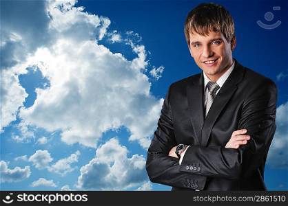 Young happy businessman over cloudy sky