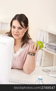 Young happy businesswoman holding apple at office having snack