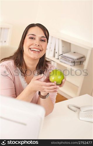 Young happy businesswoman holding apple at office having snack