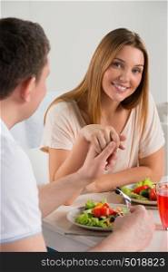 Young happy couple eating vegetable salad and holding each other hands