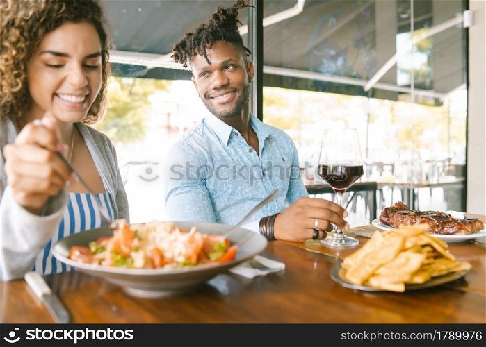 Young happy couple enjoying together while on a date at a restaurant.