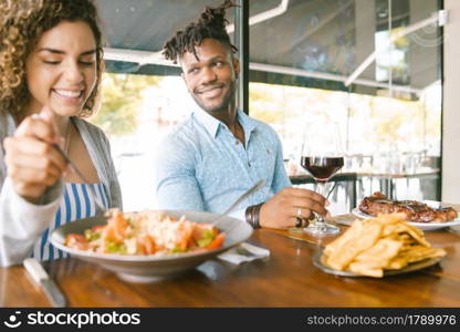 Young happy couple enjoying together while on a date at a restaurant.