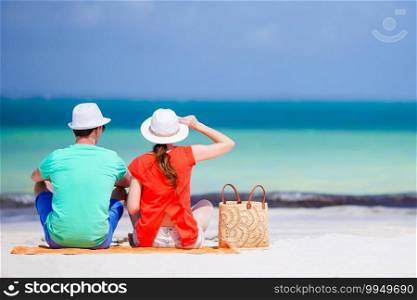 Young happy couple have fun during beach vacation. Young couple on white beach. Woman in red shirt and beach bag
