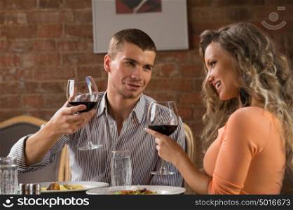 Young happy couple having romantic date at restaurant - drinking wine and eating gourmet food
