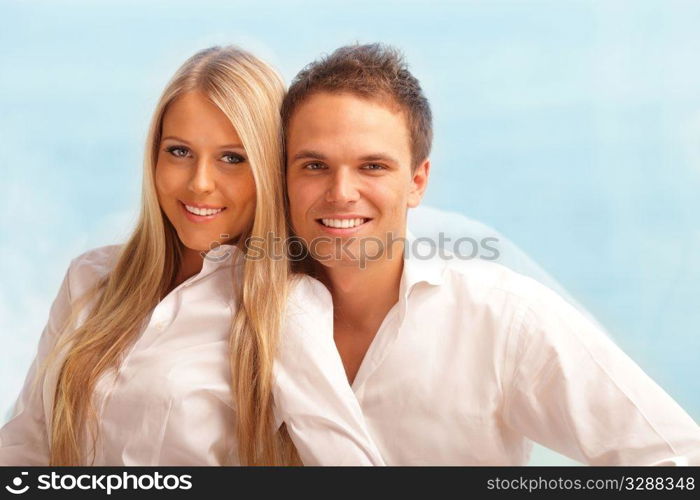 Young happy couple hugging at home with a beautiful seaview behind their window