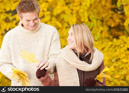 Young happy couple in love holding leaves in autumn park