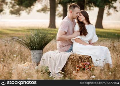 young happy couple in love sitting on straw stack in summertime in the park. Man and woman hugging, sunlight in summer meadow. The concept holiday. valentine&rsquo;s day.. young happy couple in love sitting on straw stack in summertime in the park. Man and woman hugging, sunlight in summer meadow. The concept holiday. valentine&rsquo;s day