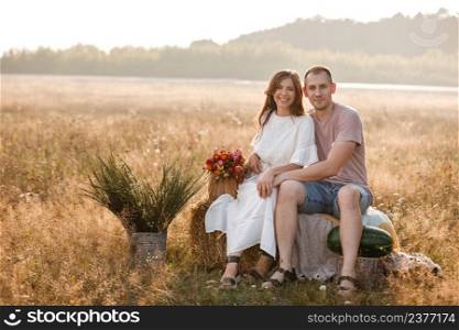 young happy couple in love sitting on straw stack in summertime in the park. Man and woman hugging, sunlight in summer meadow. The concept holiday. valentine’s day.. young happy couple in love sitting on straw stack in summertime in the park. Man and woman hugging, sunlight in summer meadow. The concept holiday. valentine’s day