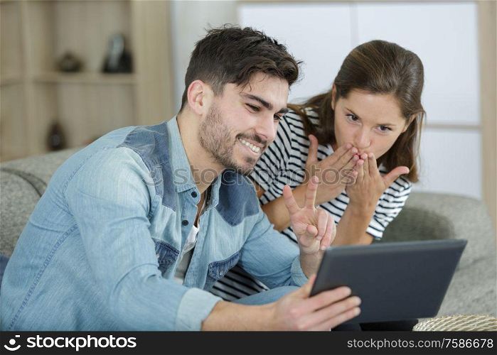 young happy couple looking at tablet and smiling