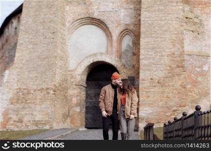 young happy couple on old city background. A love couple enjoying a walk in the courtyard of the old city. Against the background, red brick walls. selective focus.. young happy couple on old city background. A love couple enjoying a walk in the courtyard of the old city. Against the background, red brick walls. selective focus