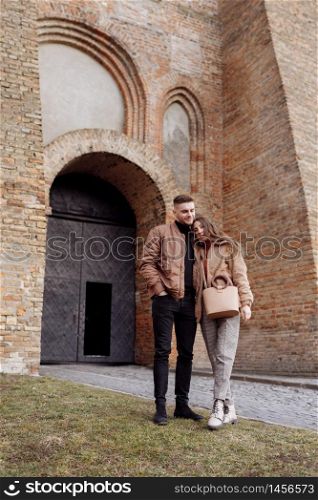 young happy couple on old city background. A love couple enjoying a walk in the courtyard of the old city. Against the background, red brick walls. selective focus. young happy couple on old city background. A love couple enjoying a walk in the courtyard of the old city. Against the background, red brick walls. selective focus.