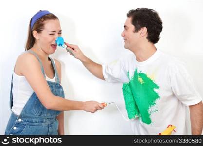 Young happy couple playing with paint against white background