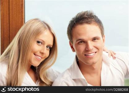 Young happy couple relaxing at home with a seaview behind their window