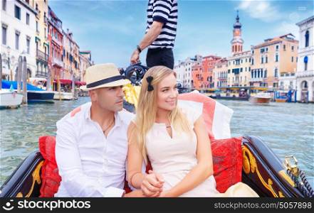 Young happy couple riding on a gondola on Grand Canal in Venice, with pleasure spending honeymoon in Europe