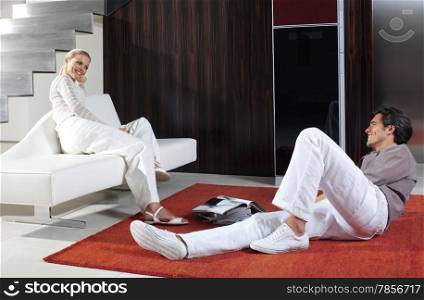 Young happy couple sitting on sofa and floor