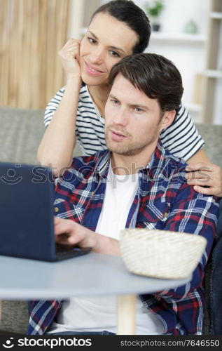 young happy couple using laptop in their apartment