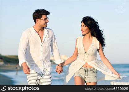 Young happy couple walking in a beautiful beach. Funny Man and woman wearing casual clothes.