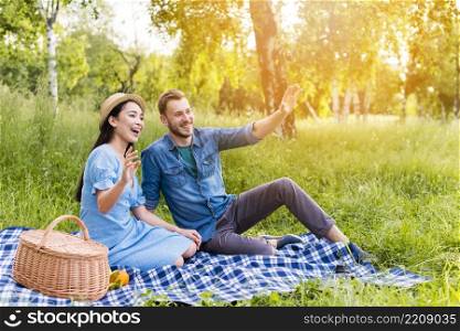 young happy couple waving smiling picnic nature