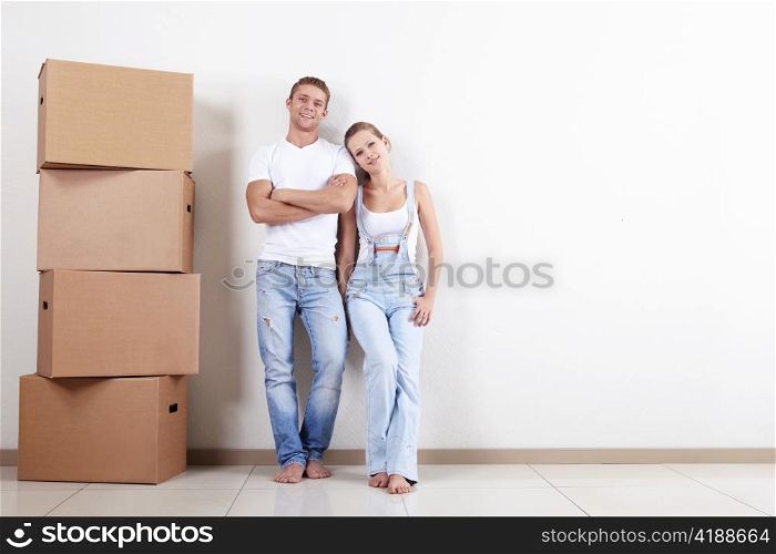 Young happy couple with boxes in apartment