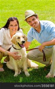 Young happy couple with Labrador dog smiling in park