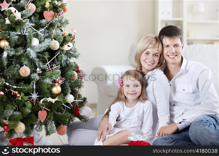 Young happy family at the Christmas tree at home