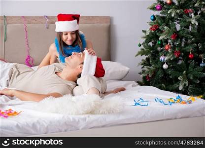 Young happy family celebrating christmas in bed