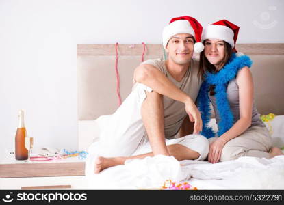 Young happy family celebrating christmas in bed