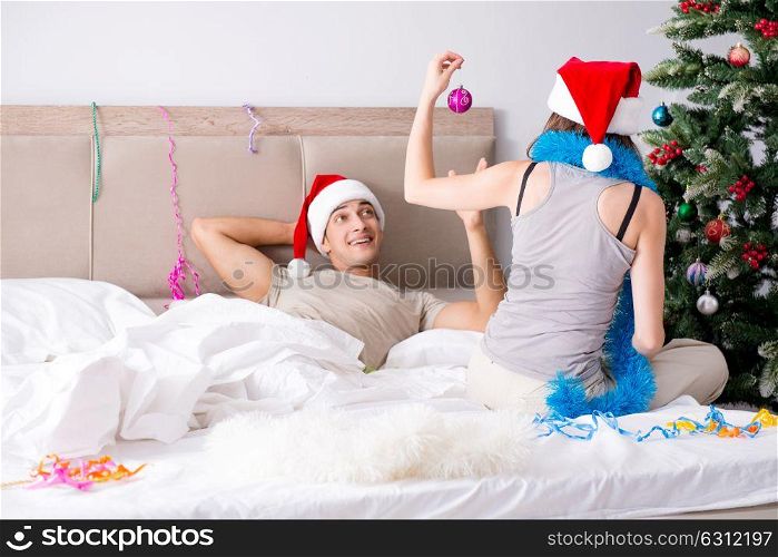 Young happy family celebrating christmas in bed. The young happy family celebrating christmas in bed