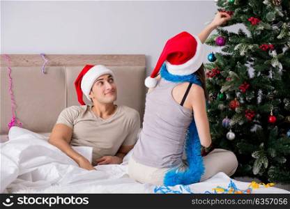 Young happy family celebrating christmas in bed. The young happy family celebrating christmas in bed
