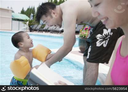 Young happy family relaxing by the pool on vacation