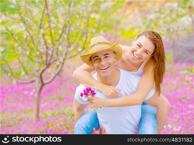Young happy family spending time together in summer garden, handsome man carry on the hands his beautiful woman, summer vacation concept