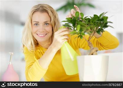 young happy female gardener spraying a bonsai