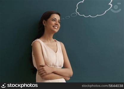 Young happy female teacher with thought bubble on chalk board