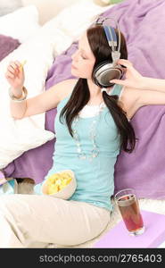 Young happy girl relax listen to music eat chips