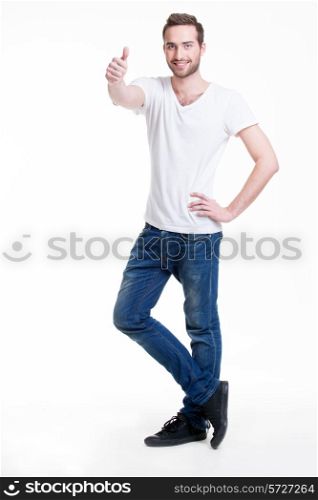 Young happy handsome man with thumbs up sign in casuals in full growth - isolated on white.