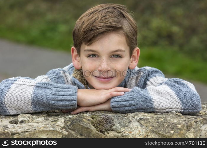 Young happy laughing male boy blond child outside leaning on his hands in autumn fall sunshine