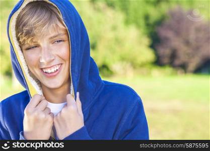 Young happy laughing male boy teenager blond child outside in summer sunshine wearing a blue hoody