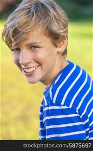 Young happy laughing male boy teenager blond child outside in summer sunshine wearing a blue striped t-shirt