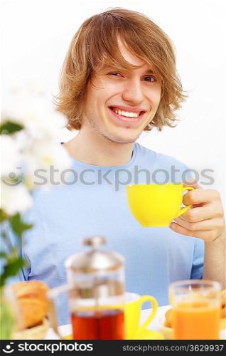 Young happy man drinking tea at home