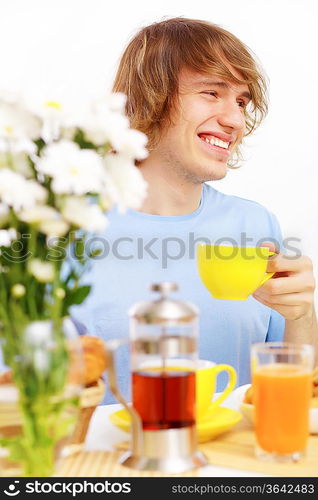 Young happy man drinking tea at home