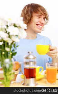 Young happy man drinking tea at home