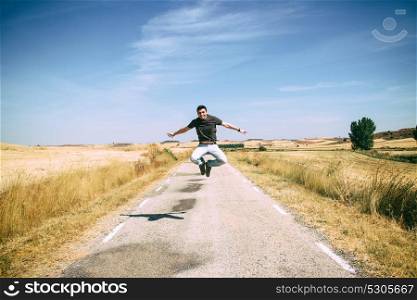 Young happy man jumping along an old road