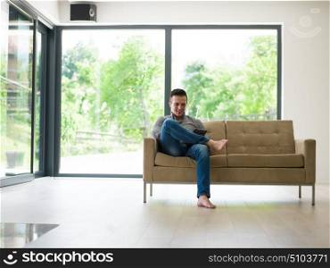 young happy man on sofa using tablet computer at luxury home