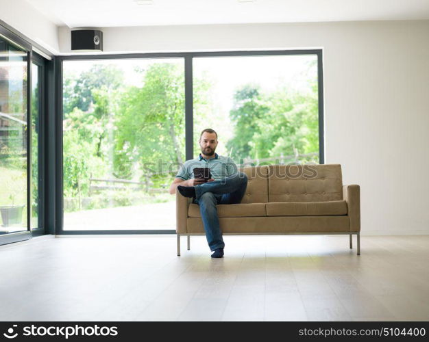 young happy man on sofa using tablet computer at luxury home