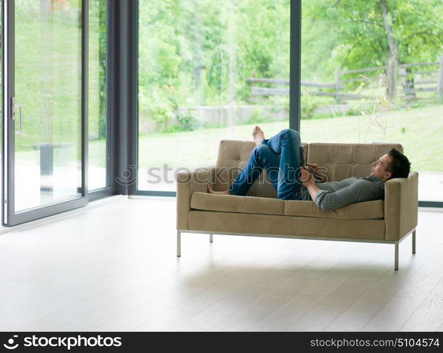 young happy man on sofa using tablet computer at luxury home