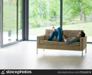 young happy man on sofa using tablet computer at luxury home