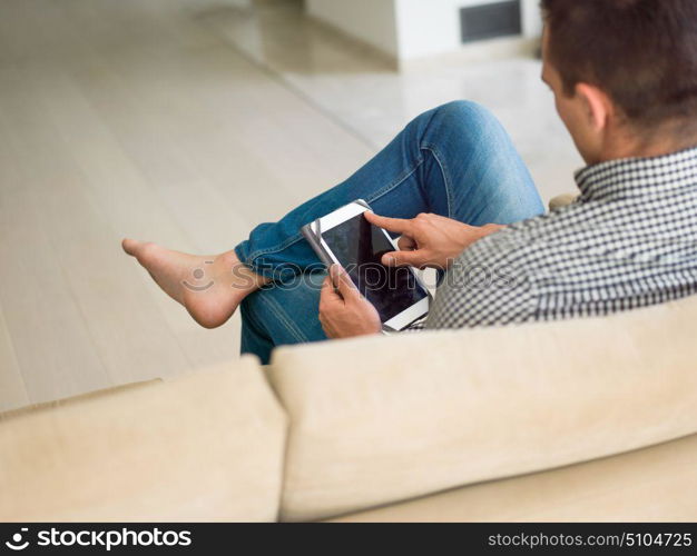 young happy man on sofa using tablet computer at luxury home