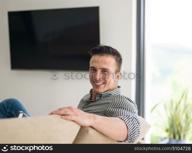 young happy man on sofa using tablet computer at luxury home